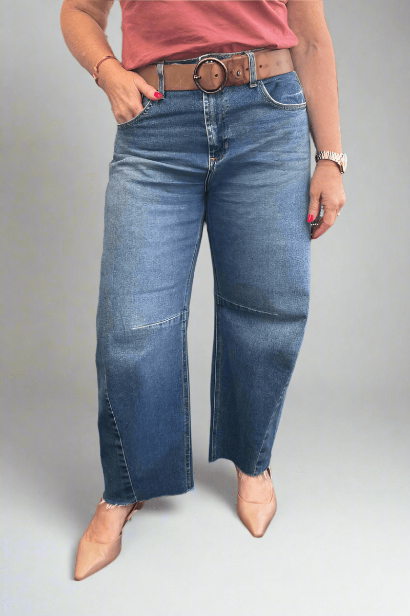 Woman wearing a barrel style blue jean with a pointed nude shoe.
