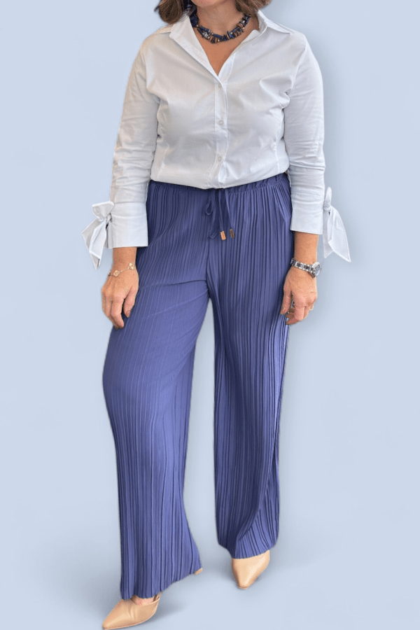 Person wearing a white blouse and blue striped pants on a light blue background