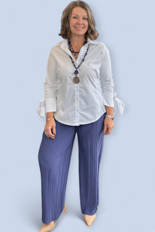 Woman wearing blue pants and white blouse.