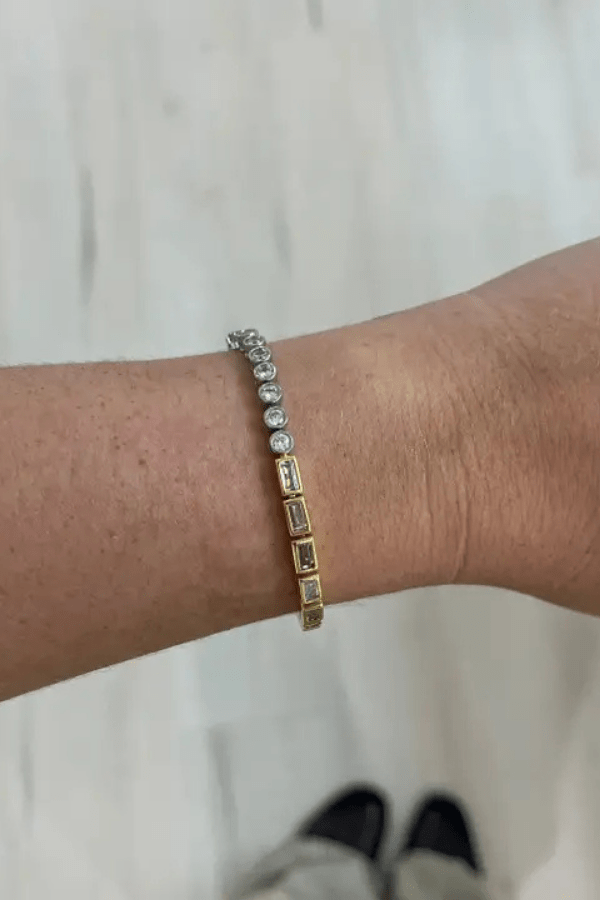 Gold bracelet on a wrist with a neutral background