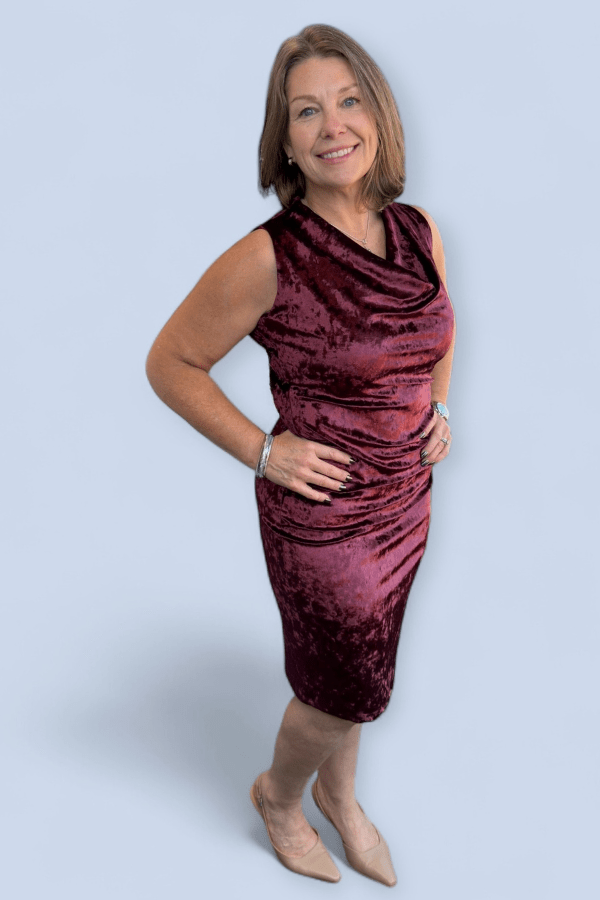 Woman wearing a burgundy velvet dress against a light gray background