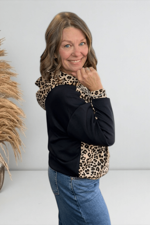 Woman wearing a black top with leopard print accents against a white background