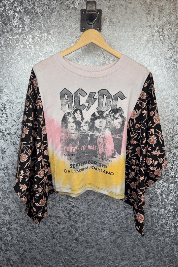 Floral-patterned shirt with AC/DC graphic on a hanger against a textured wall.