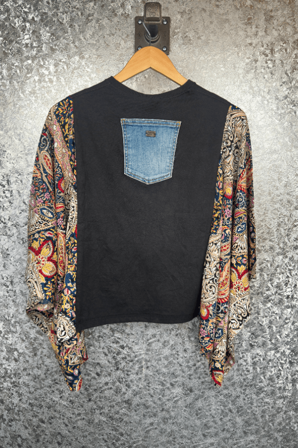 Black shirt with a denim pocket design on a hanger against a textured gray background