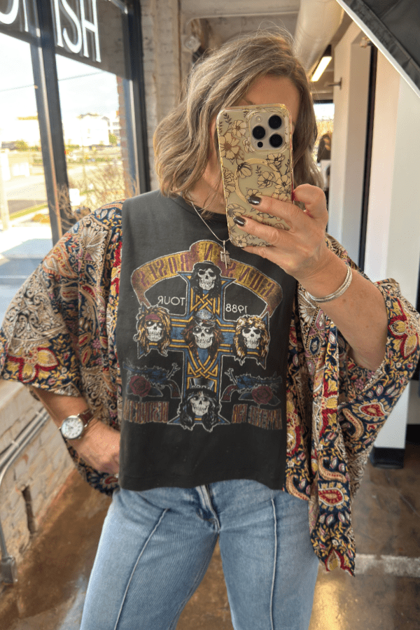 Person wearing a graphic t-shirt with a colorful pattern, standing indoors.