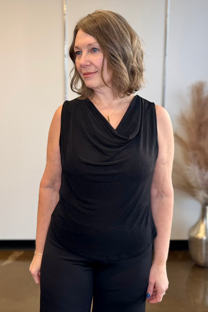 Woman modeling a black cowl neck top and black pants.