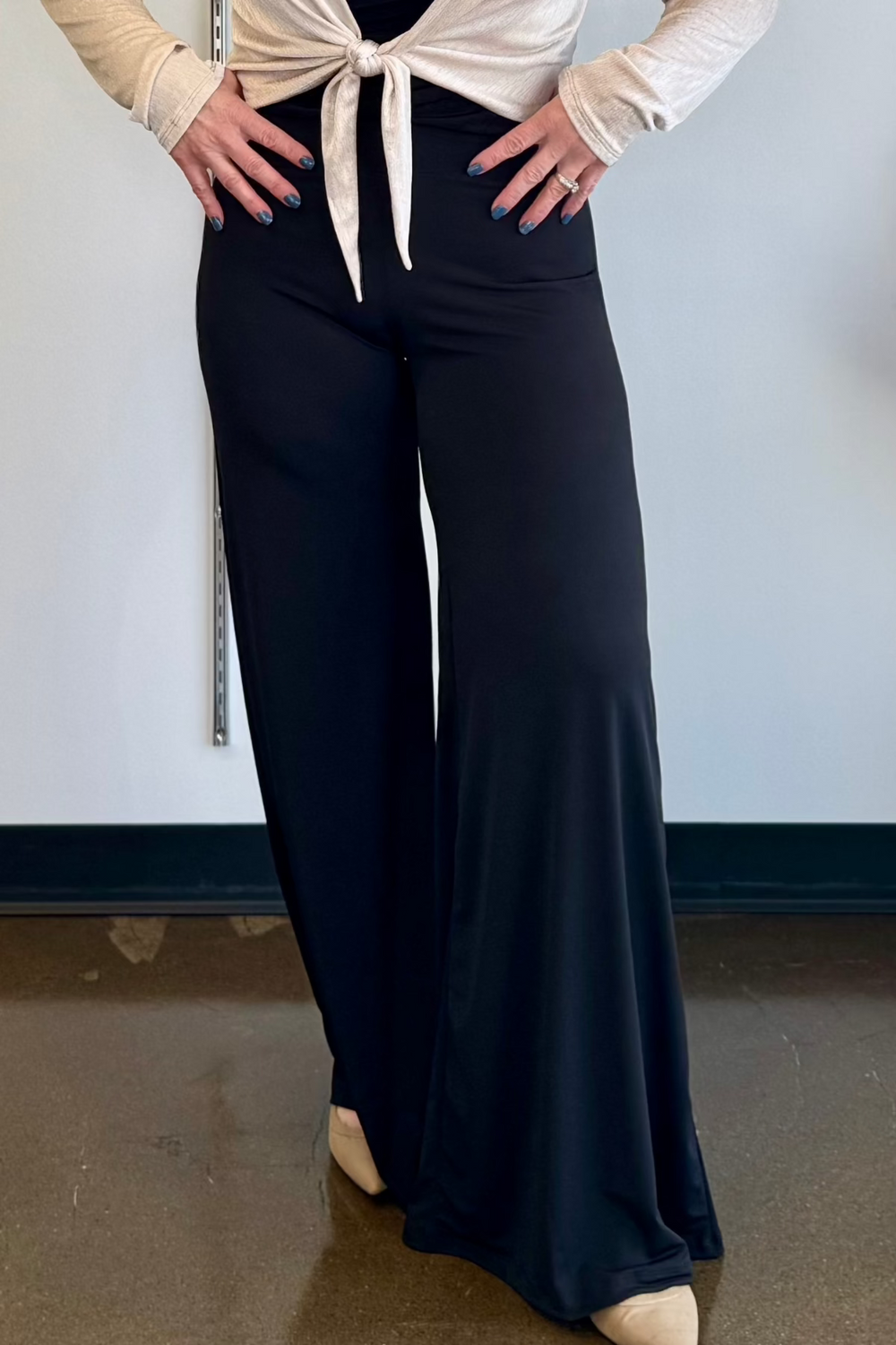 Woman wearing a black wide leg pant shown from the waist down.