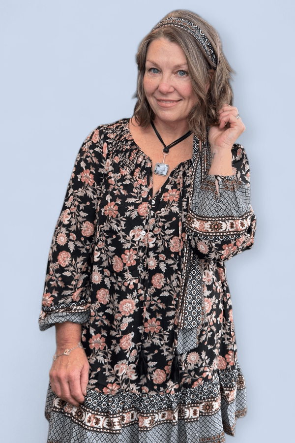 Woman wearing a floral dress with a patterned headband against a light blue background