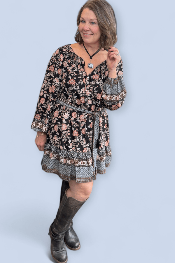 Woman wearing a floral dress with long sleeves against a light blue background