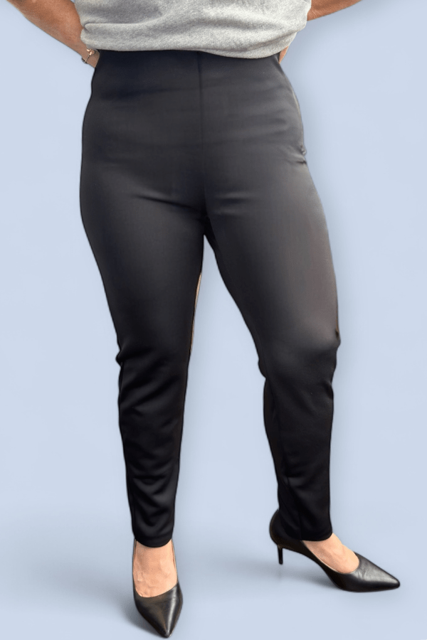 Person wearing black pants and black shoes on a light blue background