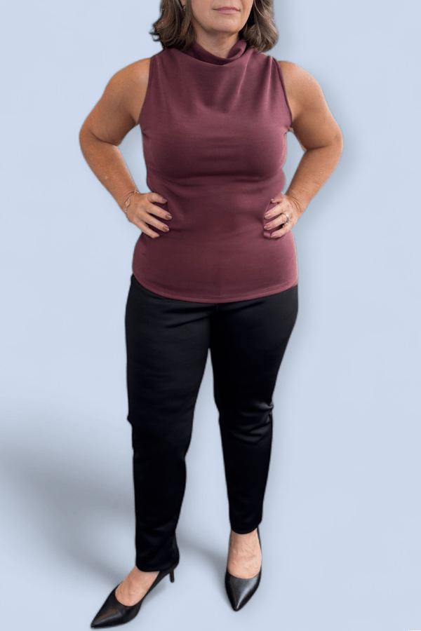 Woman wearing a maroon sleeveless top and black pants against a light blue background