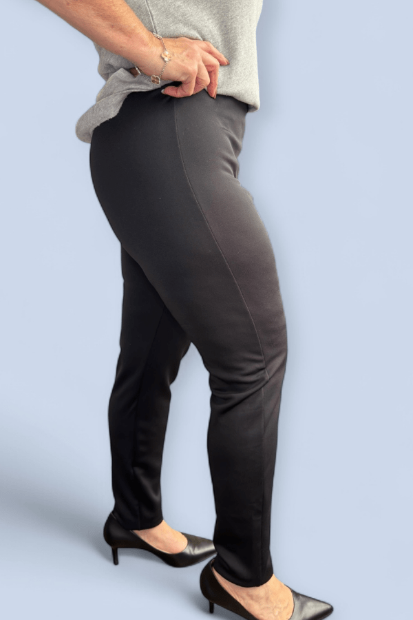 Person wearing black pants and a gray top on a light blue background