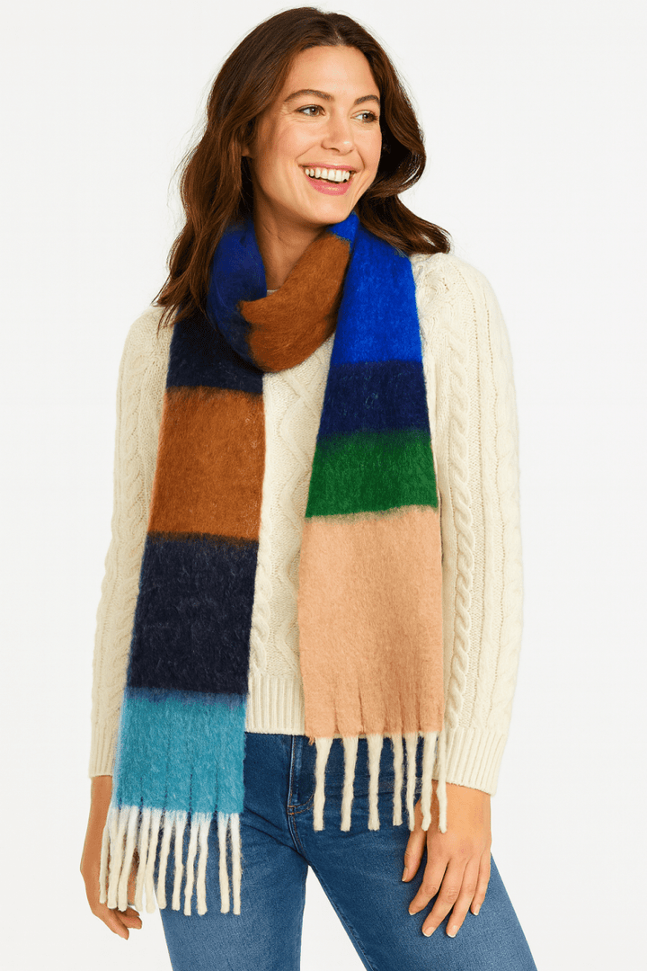 Woman wearing a blue color block scarf over an ivory sweater.