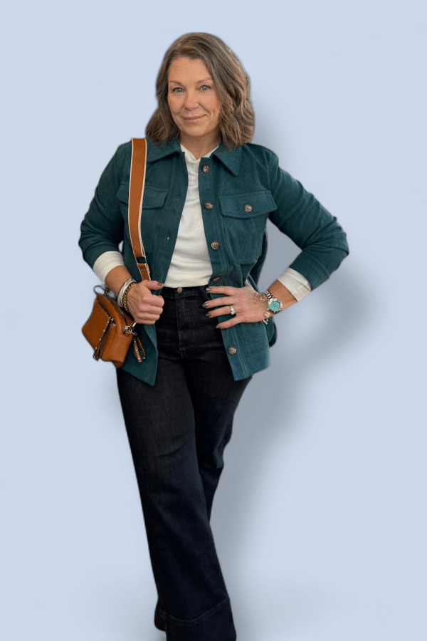 Woman wearing a green jacket and black pants against a light blue background