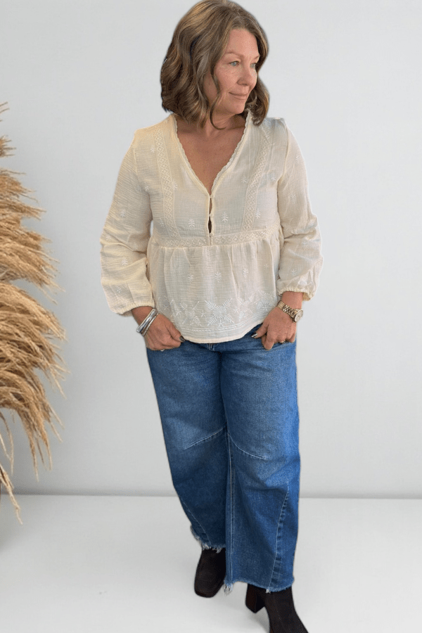 Woman in an ivory boho top and jeans.