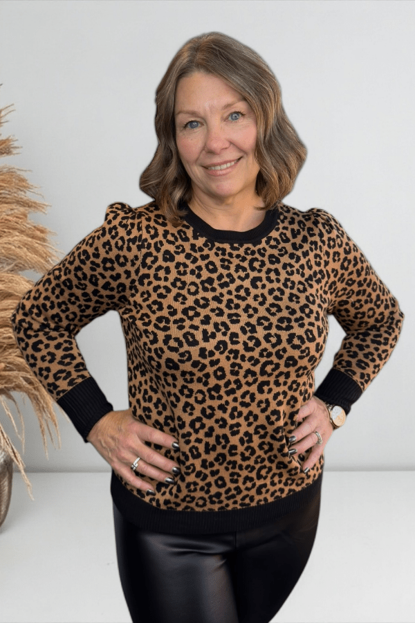 Woman wearing a leopard print sweater with a plain background