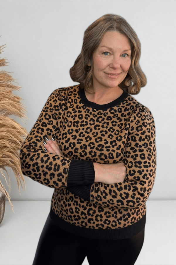 Woman wearing a leopard print sweater with black cuffs against a white background