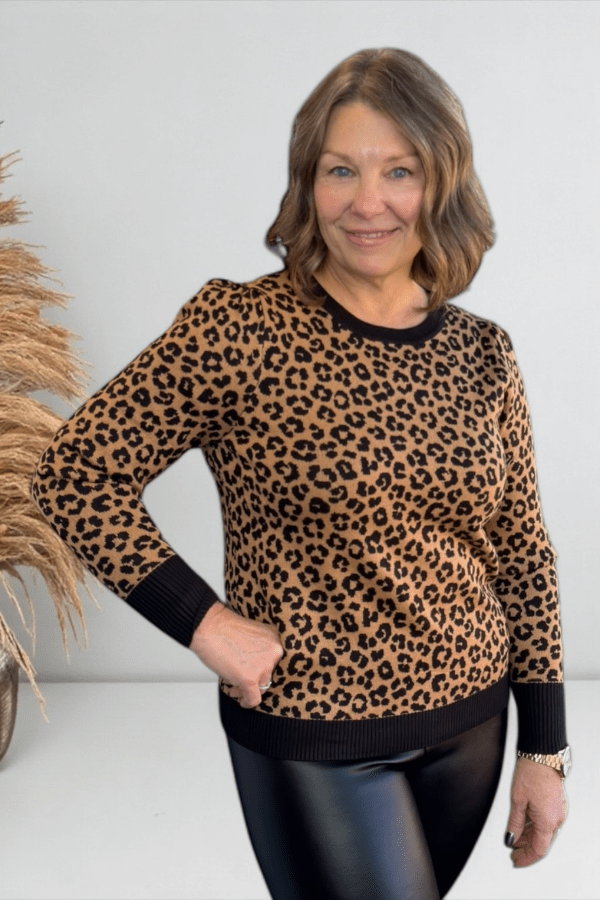 Woman wearing a leopard print sweater with a plain background