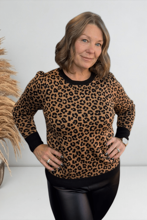 Woman wearing a leopard print sweater with a plain background