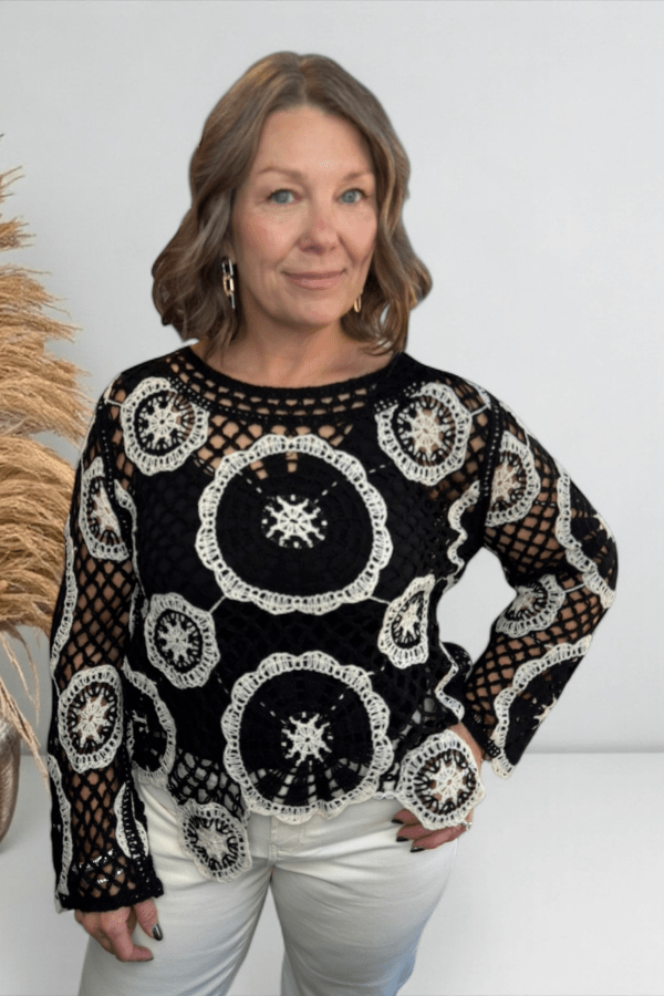 Woman wearing a black and white patterned top with a plain background