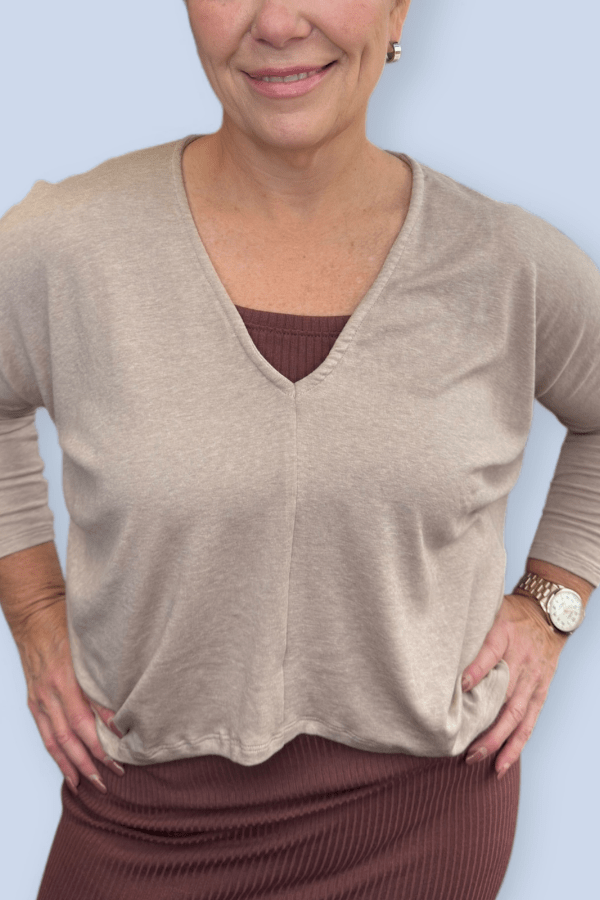 Woman wearing a neutral top over a brown ribbed tank.