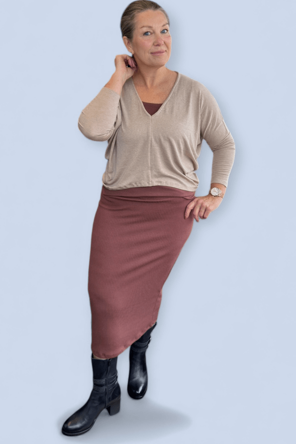 Woman wearing a tan color v neck top over a brown skirt and tank.