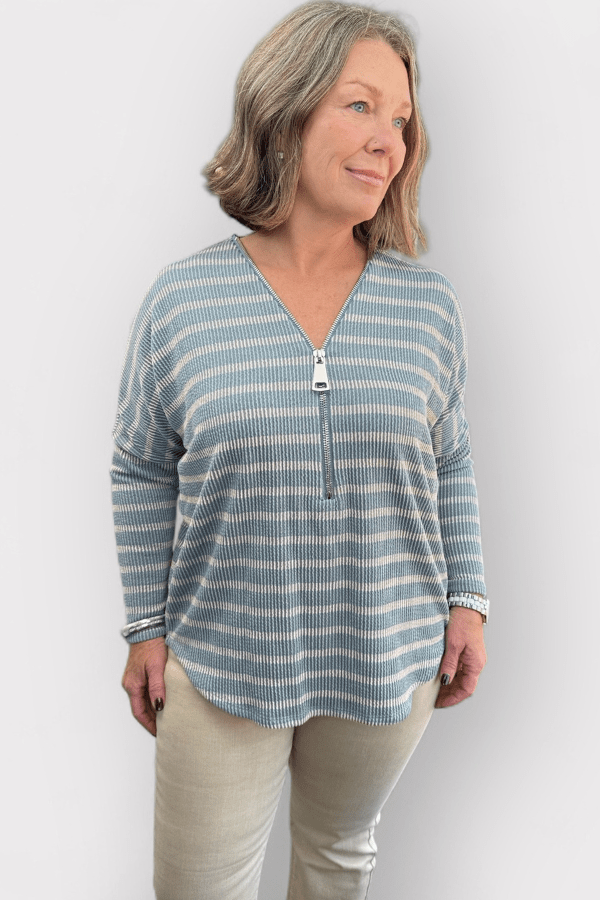 Woman wearing a blue and white striped long-sleeve top against a plain background