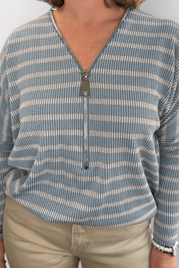 Person wearing a blue and white striped long-sleeve shirt with a zipper.