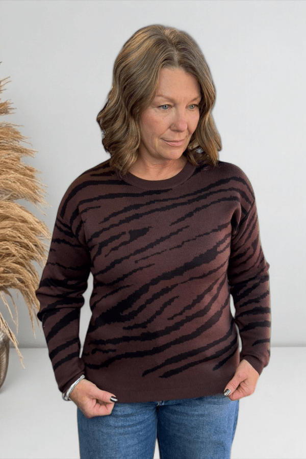 Woman wearing a brown sweater with black stripes against a white background