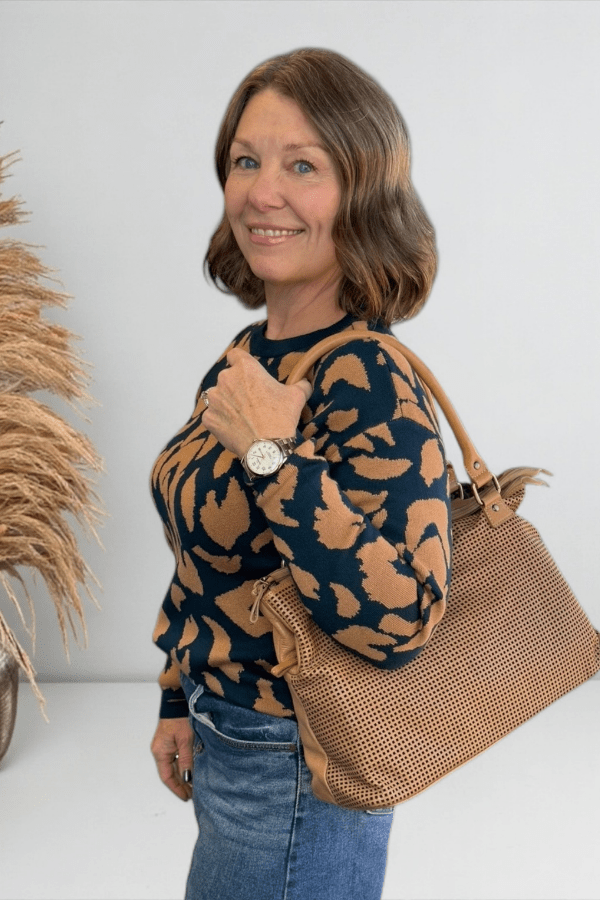 Woman carrying a camel color purse.