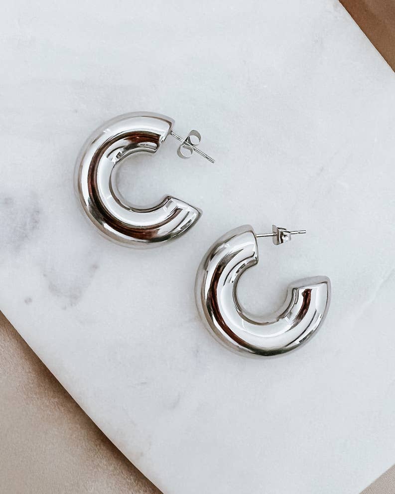 Silver hoop earrings on a marble surface