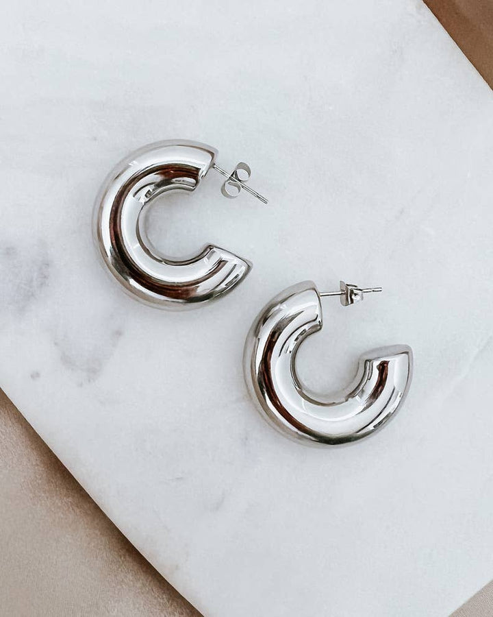 Silver hoop earrings on a marble surface