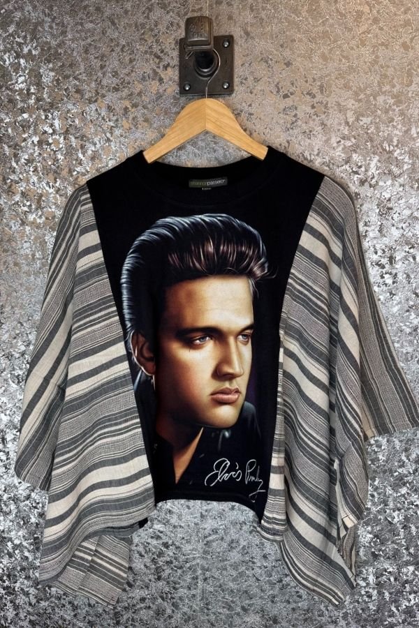 T-shirt with a portrait of a famous person on a hanger against a textured wall.