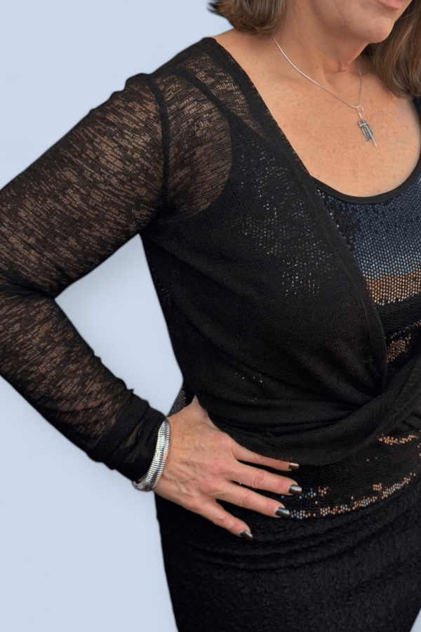 Black lace long-sleeve top worn by a person on a light blue background