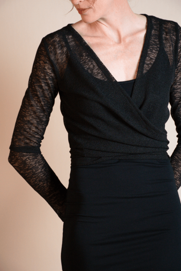 Black dress with sheer sleeves worn by a person on a beige background