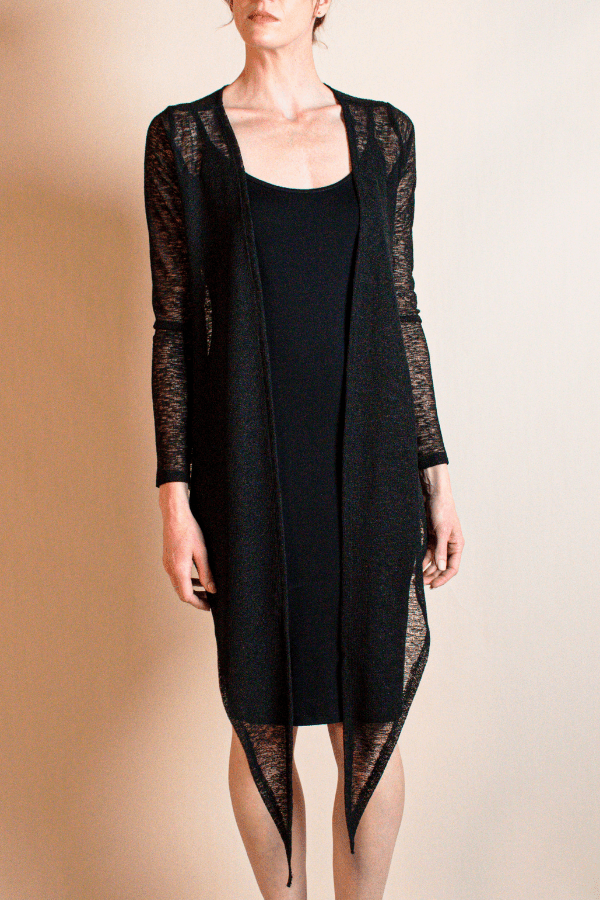 Black dress with sheer sleeves and hem on a beige background