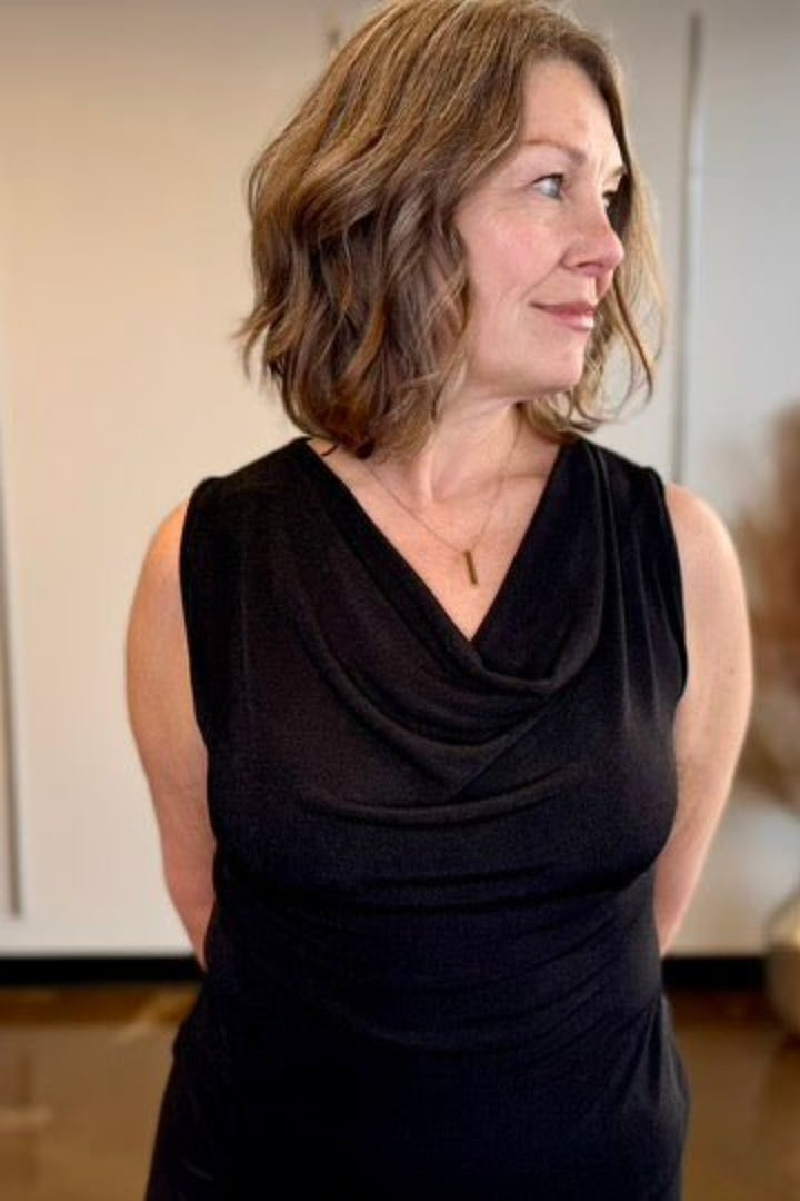 Woman wearing a black sleeveless blouse shown close up.