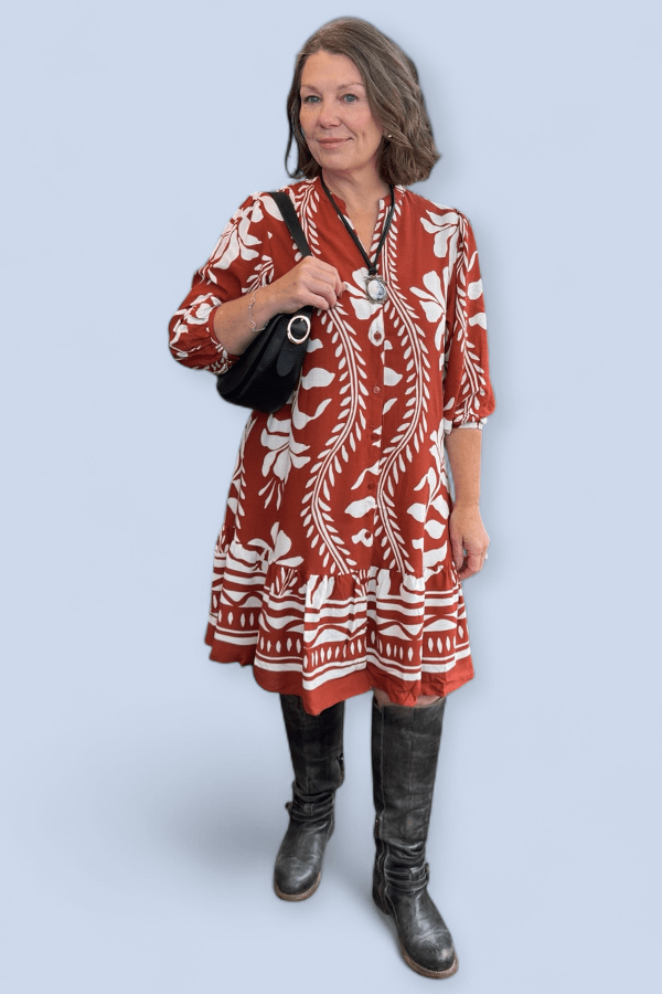 Woman wearing a red and white patterned dress with black boots on a light blue background