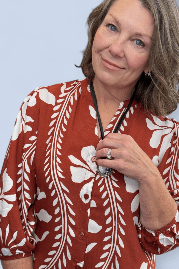 Woman wearing a red floral blouse against a light blue background