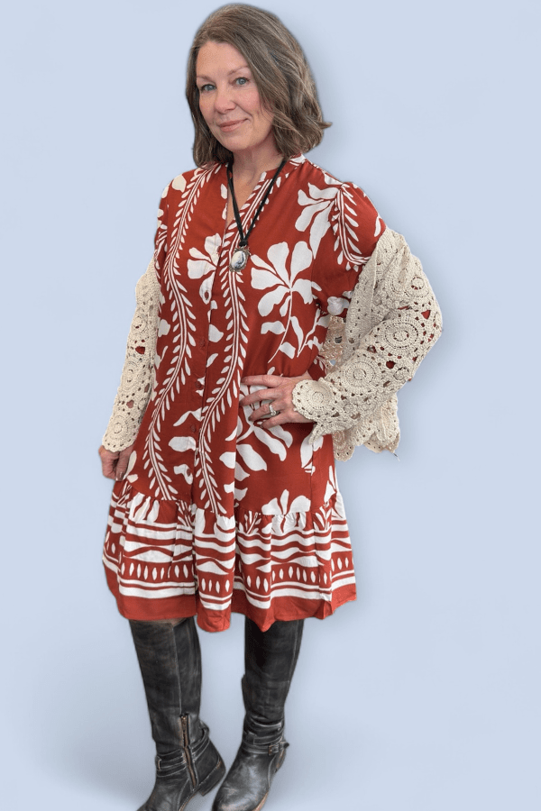 Woman wearing a red and white patterned dress with lace sleeves against a light blue background