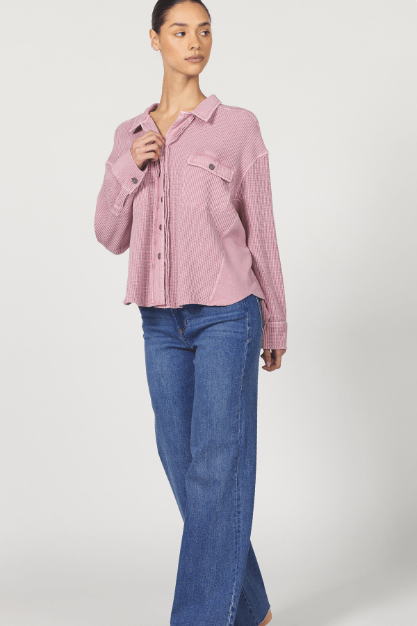 Woman wearing a pink shirt and blue jeans on a white background