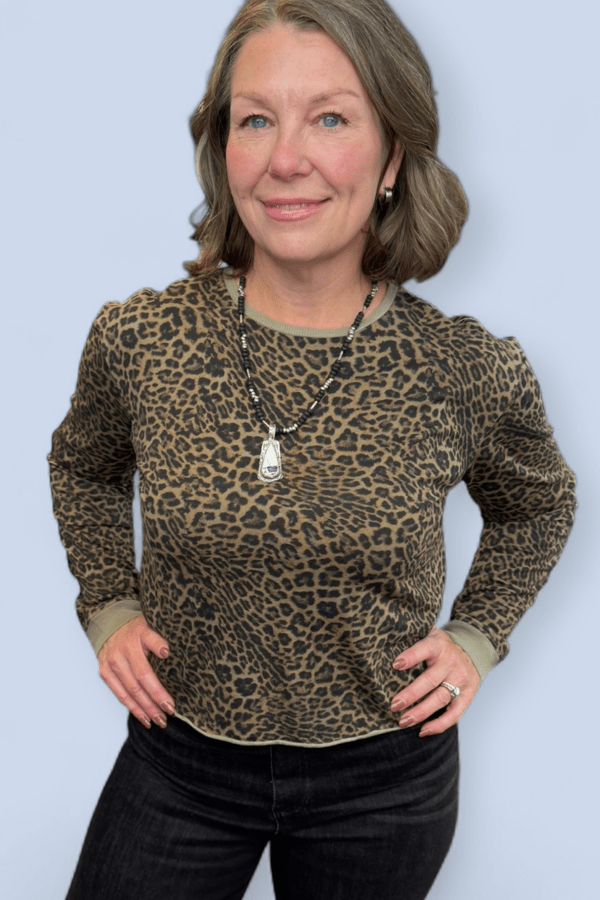 Woman wearing a leopard print sweater against a light blue background