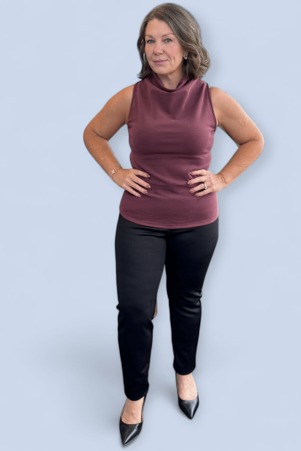 Woman wearing a sleeveless maroon top and black pants on a light blue background