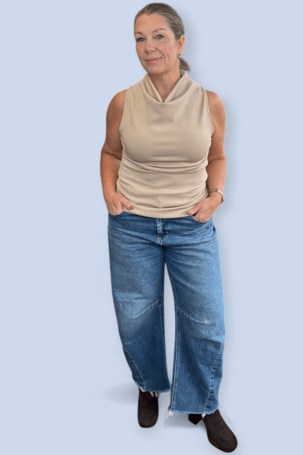 Woman wearing sleeveless top with barrel jeans.