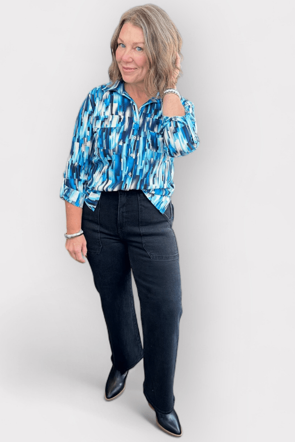 Woman wearing a blue patterned blouse and black pants on a white background