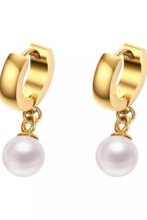 Gold huggie earring with a drop pearl against a white backdrop.