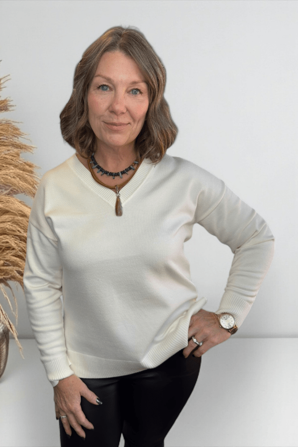 Woman wearing a cream-colored sweater with a white background