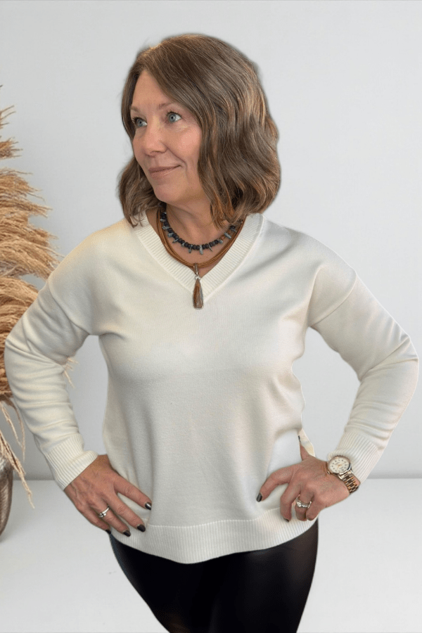 Woman wearing a cream sweater with a neutral background