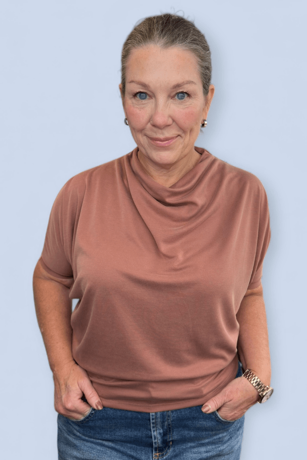 Woman wearing a brick color top.