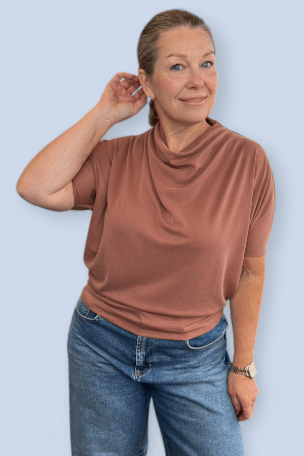 Woman modeling a rust flowy top and jeans.